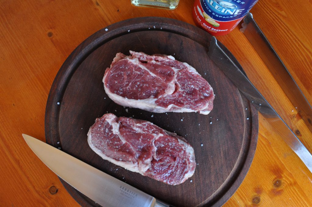 Raw slices of rib-eye steak on a wooden plate